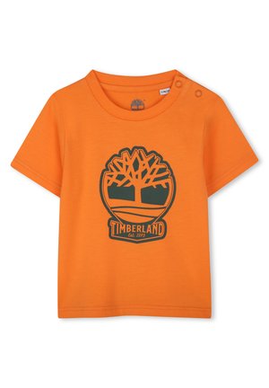 T-shirt en coton orange à manches courtes, avec un logo Timberland en vert foncé et un graphique d'arbre. Détail à pression sur l'épaule.