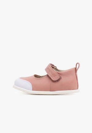 Chaussure en suède rose avec un bout et une semelle en caoutchouc blanc. Équipée d'une sangle Velcro et de bords festonnés autour de l'ouverture pour un maintien sûr.