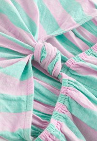 Robe légère en coton avec des rayures verticales roses et vert menthe. Elle présente un détail de nœud et une taille élastique froncée.