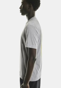 Grå bomulds T-shirt med korte ærmer, rund hals og løs pasform; har subtil tekstur og et kontrasterende grafisk design på bagsiden.