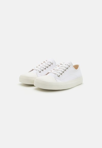 Vita canvas sneakers med en slät gummisula, snörningsstängning och metallöglor. Har en minimalistisk design och subtil textur.
