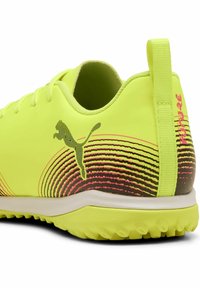 Kirkas kollane sportjalats tekstuuriga pealispinnaga, mustade ja roosade triipudega ning Puma logoga külgedel.