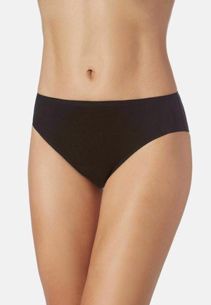 Torso femenino con ropa interior negra lisa de corte alto sobre un fondo claro y simple.