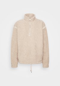 Beige fleece-tröja med hög krage, halvdragkedja fram, sidopaneler och justerbar dragsko i nederkant. Mjuk, texturerad tyg.