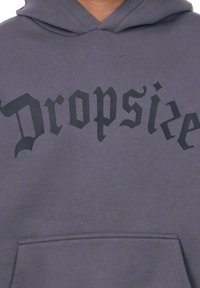 Szara bluza z kapturem z czarnym, gotyckim nadrukiem, na którym widnieje napis "Dropside". Posiada kieszeń z przodu oraz regulowany kaptur.