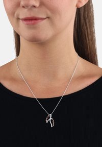 Collana d'argento con ciondolo a forma di foglia, impreziosita da dettagli in oro rosa e simil-diamanti, indossata su una maglia nera.
