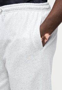 Φωτεινό γκρι φόρμα από απαλό ύφασμα με ελαστική ζώνη μέσης και πλαϊνές τσέπες. Διαθέτει ένα μικρό λευκό λογότυπο Nike στο αριστερό μηρό.