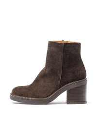 Brown suede ankle boot with a rounded toe, side zip closure, and a wooden block heel. Features contrasting stitching along the sole.