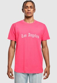 Rožinė medvilninė marškinė su baltu, stilizuotu „Los Angeles“ grafiniu dizainu. Trumpomis rankovėmis, apvaliu iškirpimu, laisvu siluetu, glotnia tekstūra.
