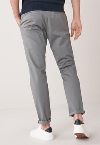 Gray chinos with a slim fit, featuring rolled cuffs, side pockets, and back pockets, paired with white sneakers with black accents.