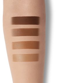Five swatches of foundation on a light skin tone arm, ranging from deep to light brown shades, with varying finishes from matte to glossy.
