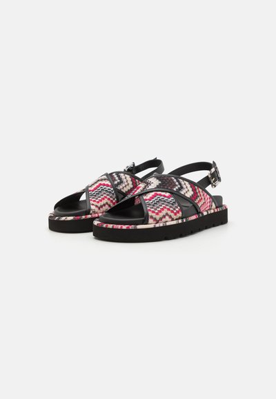 Sandales plates texturées avec un motif en zigzag en rose, noir et crème ; dotées de sangles ajustables et d'une semelle noire solide.