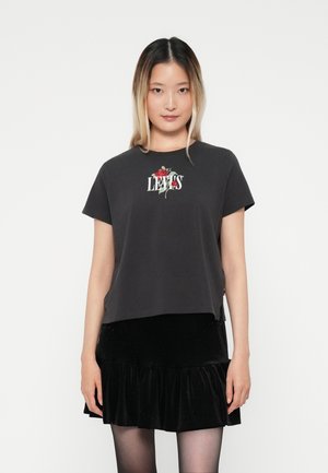 T-shirt gris à manches courtes avec le texte "LEVI'S" et une broderie de rose sur la poitrine, associé à une jupe noire en velours avec des volants.
