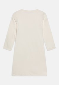 Vaaleanbeige pitkähihaiset mekko, jossa on pyöreä pääntie ja suora helma. Pehmeä kangas, jossa minimaalinen tekstuuri, ilman lisäkuvioita tai korostuksia.