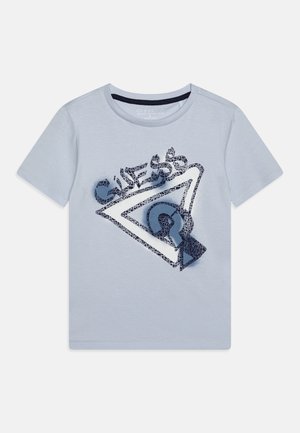 Lyseblå t-shirt med korte ærmer med en stor marineblå og hvid trekantet GUESS-logo og et tekstureret mønster foran.