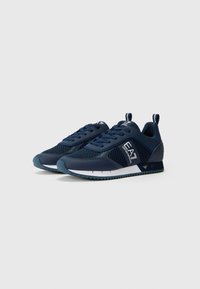 Navy training shoes with a mesh upper, padded collar, and rubber sole. Features include laces and a logo accent on the side.