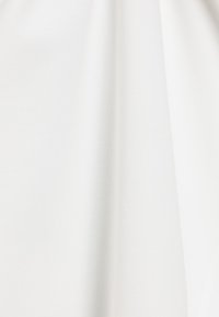 Witte stof met een gladde textuur en een matte afwerking, vertonend subtiele plooien en drapering, wat wijst op lichtgewicht materiaal.