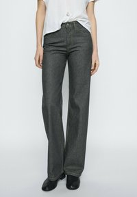 Donkergrijze denim jeans met een recht gesneden ontwerp, voorzien van gele stiksels en een klassieke knopen- en rits sluiting. Gekocht met zwarte enkellaarsjes.