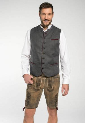 Grauer Wollweste mit burgunderfarbenen Akzenten, Knopfverschluss, kombiniert mit braunen Leder-Shorts mit floralen Stickereien und seitlichen Bindebändern.