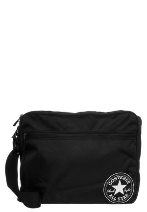 Sac bandoulière noir Converse All Star avec une poche avant zippée, une bandoulière réglable et un logo circulaire en bas à droite.