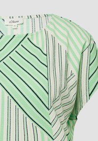Blouse rayée vert clair et blanche avec des lignes diagonales et verticales, tissu texturé et col rond, étiquette s.Oliver taille 36.