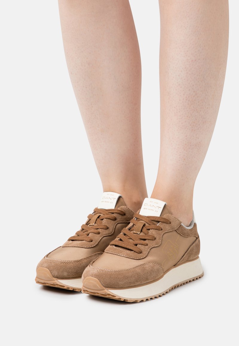 Brown sneakers made of suede and leather with a textured finish, featuring lace-up closure and white rubber sole. Logo on heel tab.