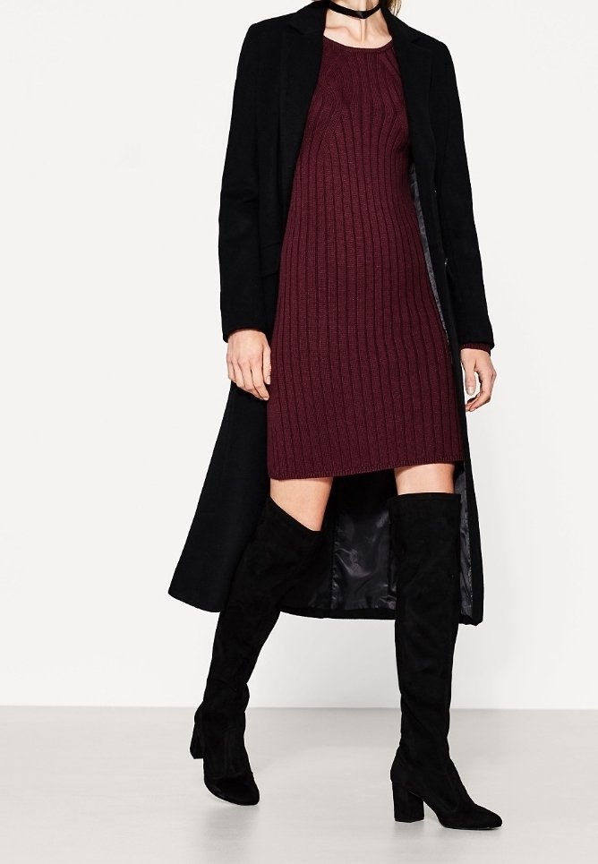 Musta villakangastakki ribatusta burgundimekosta, yhdistettynä mustiin mokkanahkaisiin reisiin ulottuviin saappaisiin, joissa on paksut korot.