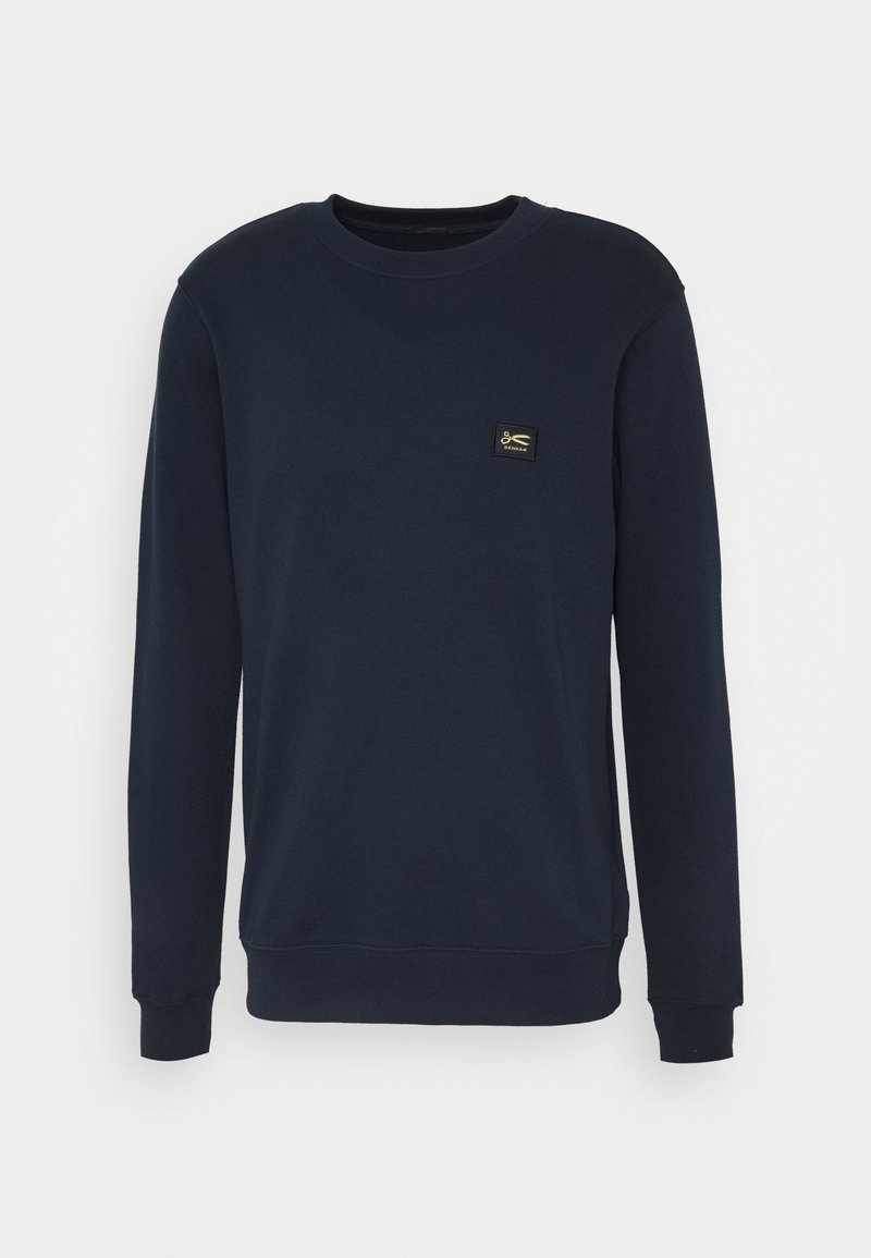 Navy blue sweatshirt made of soft fabric, featuring a crew neckline, long sleeves, and a small square logo patch on the chest.