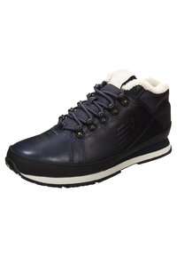 Navy blue leather hiking shoe with white fleece lining, metal eyelets, and black rubber outsole; features textured surface and logo detail.