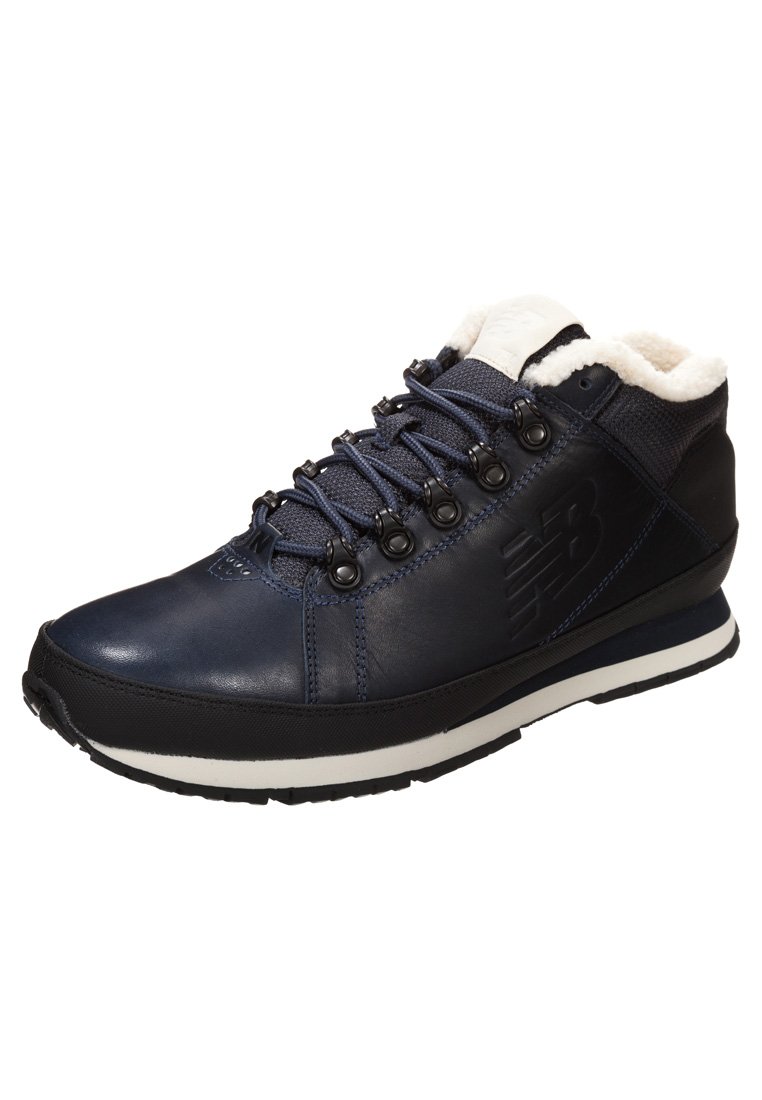 Navy blue leather hiking shoe with white fleece lining, metal eyelets, and black rubber outsole; features textured surface and logo detail.