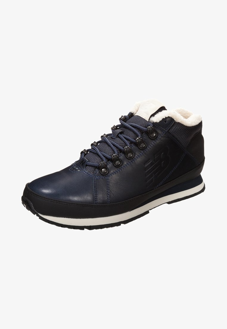 Navy blue leather hiking shoe with white fleece lining, metal eyelets, and black rubber outsole; features textured surface and logo detail.