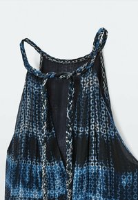 Sininen ja musta kuvioitu toppi, jonka olkapäätön malli sisältää syvän kaula-aukon, letitetyt hihat ja lentävän kankaan tekstuurin.