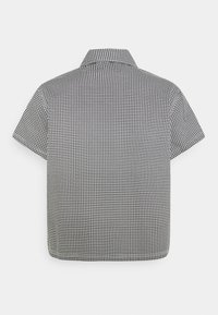 Camicia a maniche corte con motivo pied de poule bianco e nero, collo classico e taglio dritto nell'orlo.