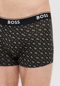 Ανδρικά μπόξερ σε μαύρο και χακί με γεωμετρικό σχέδιο διαπλεκόμενο. Διαθέτουν μαύρη ελαστική μέση με το λογότυπο "BOSS". Απαλό βαμβακερό υλικό.