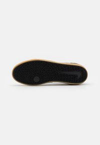 Suela de zapato de goma negra con intrincado patrón de espiga, con un borde de color goma y un distintivo logotipo de Nike.
