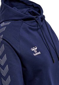 Marineblaues Hoodie mit Kordelzug und besticktem Logo. Verfügt über weiße Chevron-Muster an den Ärmeln. Hergestellt aus einem weichen Stoff.