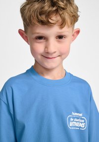 Lichtblauw katoenen T-shirt met een ronde hals, korte mouwen en een wit bedrukt logo op de voorkant, met een relaxte pasvorm.