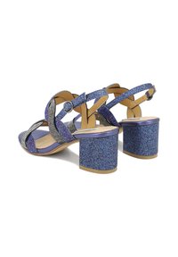 Sandali con tacco alto glitterati viola, con cinghie incrociate, un tacco a blocco e decorazioni in argento. Soletta liscia e cinturino alla caviglia regolabile.