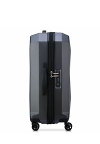 Valigia rigida grigio scuro in posizione verticale, con quattro ruote girevoli, maniglia laterale e combinazione TSA integrata.