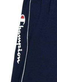 Pantalones cortos deportivos de color azul marino con el logo "Champion" impreso en blanco de forma vertical. Presentan piping lateral blanco y una textura suave de algodón.
