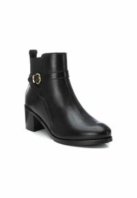 Botas de tobillo de cuero negro con tacón de bloque, que presentan un detalle de hebilla dorada y panel lateral elástico. Textura suave y diseño elegante.