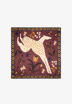 Wzorzysty dywanik z białą postacią skaczącą, pokrytą żółtymi plamami na głębokim czerwonym tle. Kwiatowe akcenty w żółtym, niebieskim i zielonym. Dekoracyjna ramka.