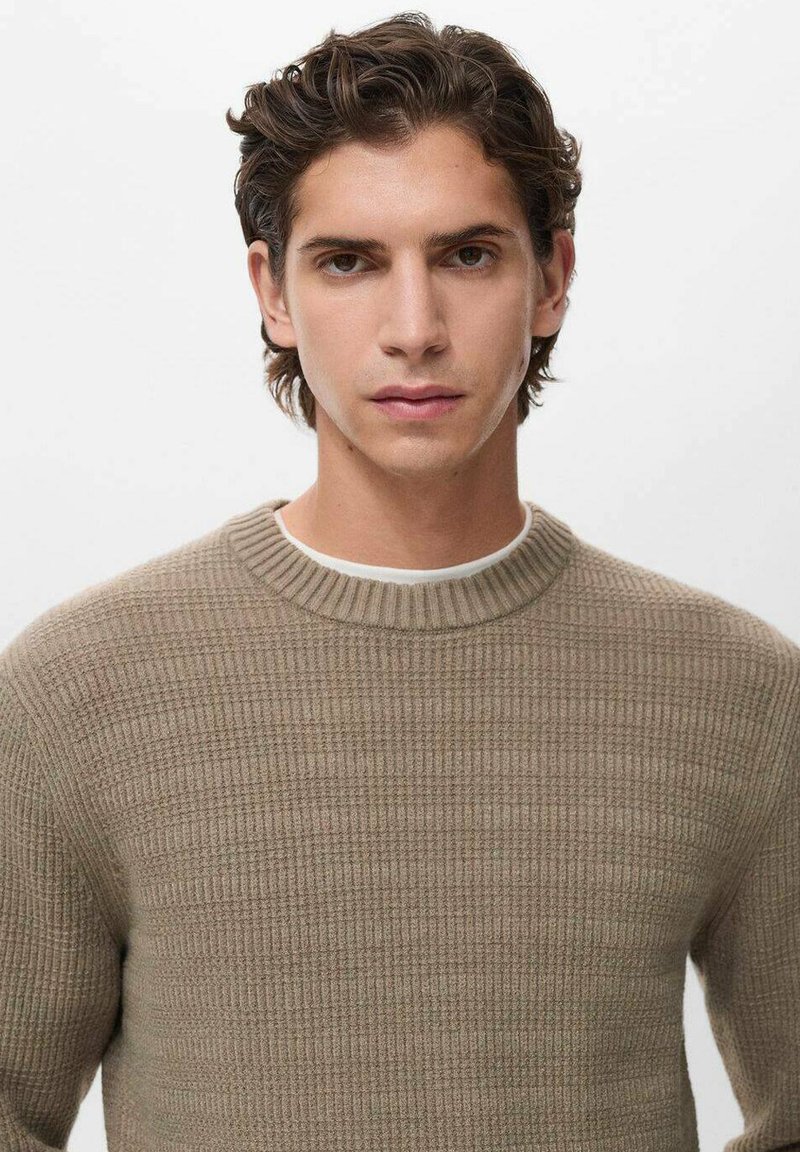 Maglione beige lavorato a maglia con una trama a costine, dotato di scollo rotondo e maniche lunghe. Design semplice senza motivi o dettagli.