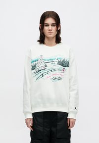 Sweatshirt branca com um gráfico de paisagem de inverno com árvores, montanhas e um esquiador em rosa. Punhos canelados e um logo na manga.