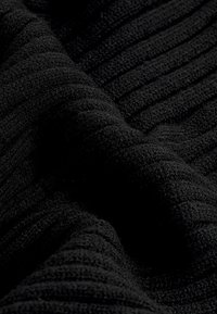 Zwarte textuurstof met geribbelde lijnen, voorzien van een zachte, pluizige oppervlakte en subtiele, gedrapeerde plooien die de tactiele kwaliteit verbeteren.