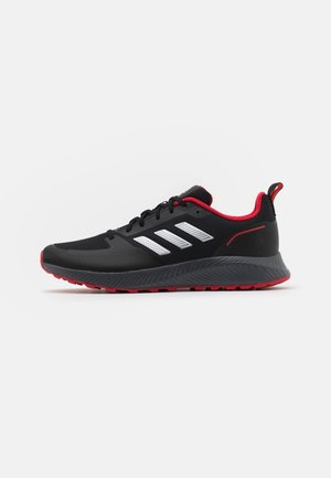 Chaussure de course noire avec semelle et doublure intérieure rouges, rayures blanches sur le côté, lacets noirs et languette au talon sur fond blanc.