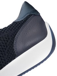 Nahaufnahme der Ferse eines dunkelblauen Sneakers mit strukturiertem Strick-Obermaterial, Lederüberzug und weißer Gummisohle.