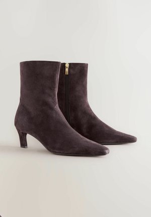 Bottines en daim gris foncé avec un bout pointu, un talon de 5 cm et une fermeture éclair sur le côté avec un accent doré. Texture lisse et design élégant.