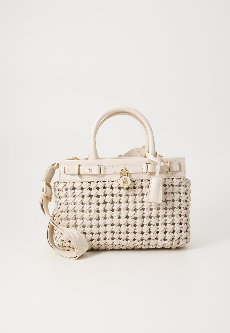 Sac à main tissé beige avec deux poignées, une bandoulière amovible et un petit détail de serrure dorée sur la ceinture supérieure.