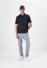 Tumesinine polo särk klassikalise kraega, lühikeste varrukatega ja kitsas lõige, kooskõlastatud heledate hallide pükstega ja valgete tossudega.